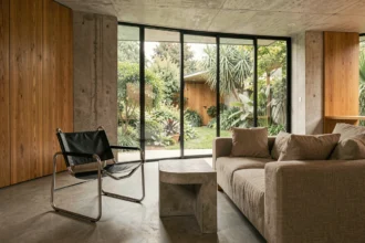 Intérieur moderniste inspiré de Marcel Breuer avec chaise Wassily en chrome, béton brut et baies vitrées donnant sur jardin